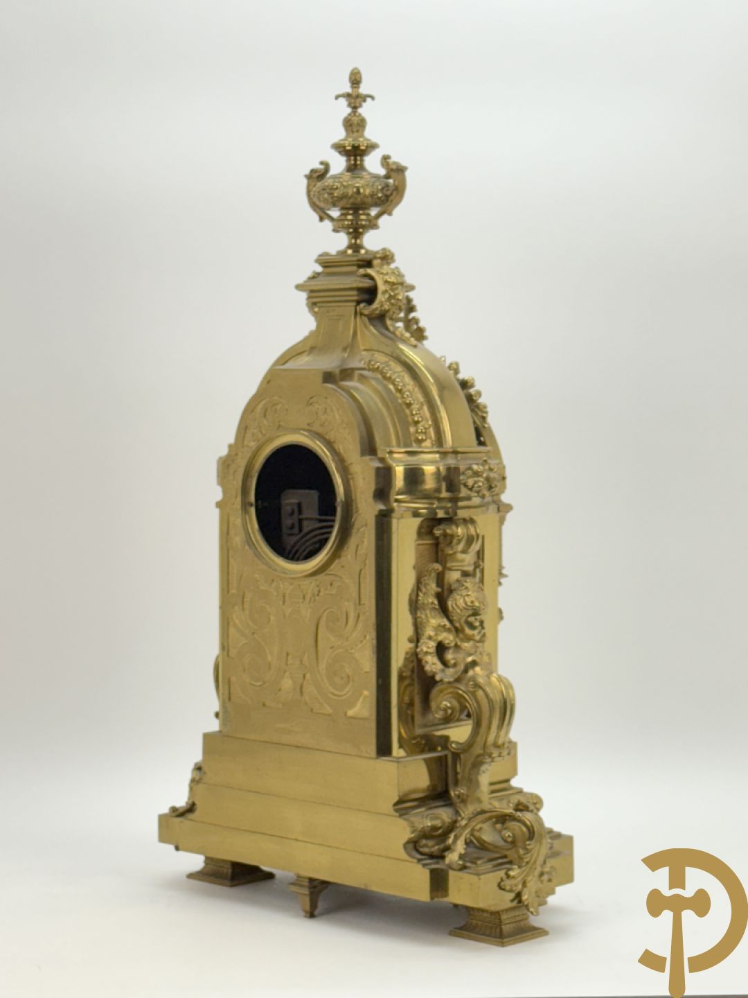 Vuurvergulde bronzen pendule, zijdelings bezet met gevleugelde dames, bovenaan met amfoor