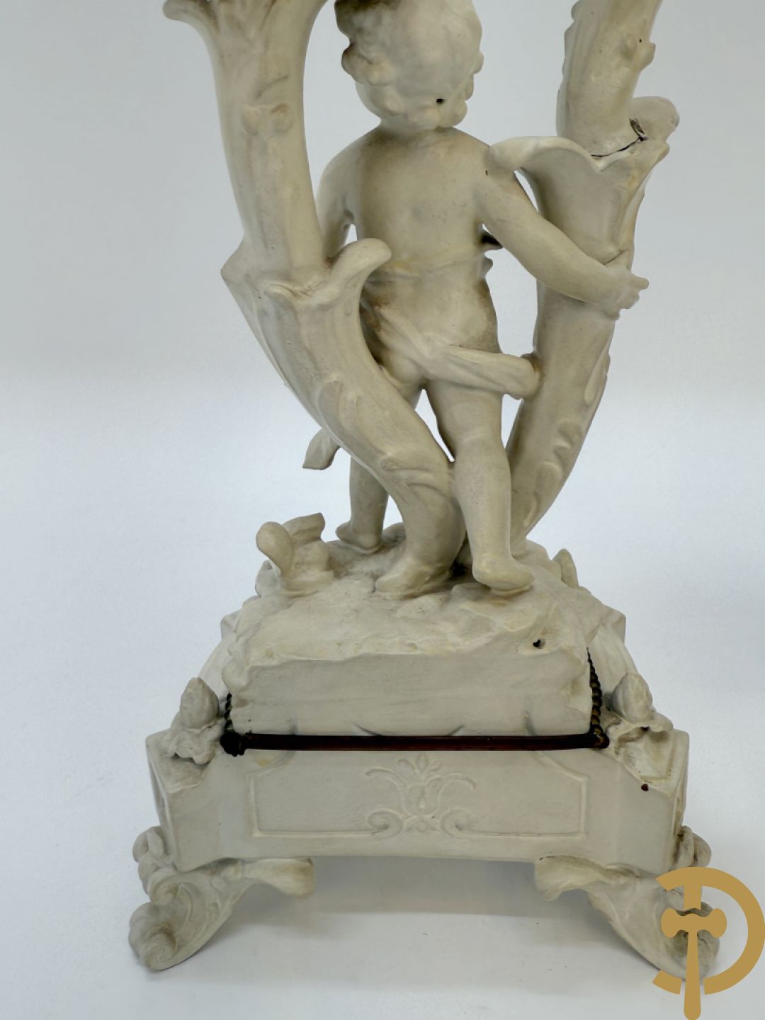 Driedelige porseleinen garnituur bestaande uit pendule bezet met lieftallig koppel, geflankeerd door paar kandelaars met cupido