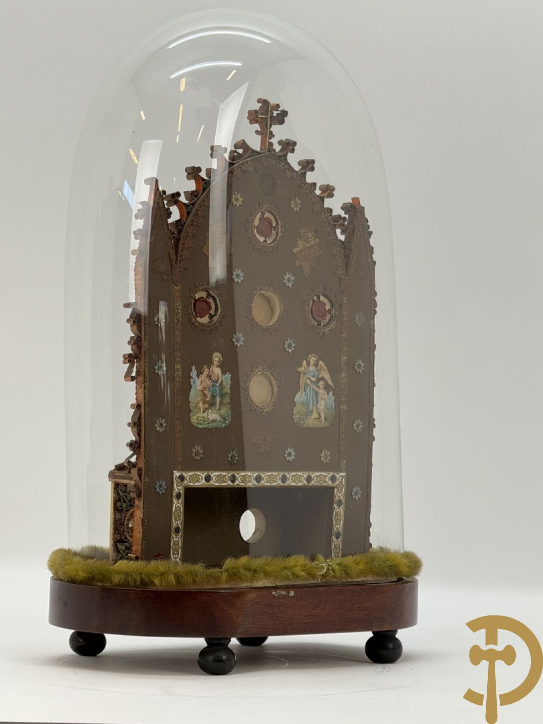 Relikwiehouder in de vorm van een altaar met Christusnagel en omgeven door papperollen - onder stolp