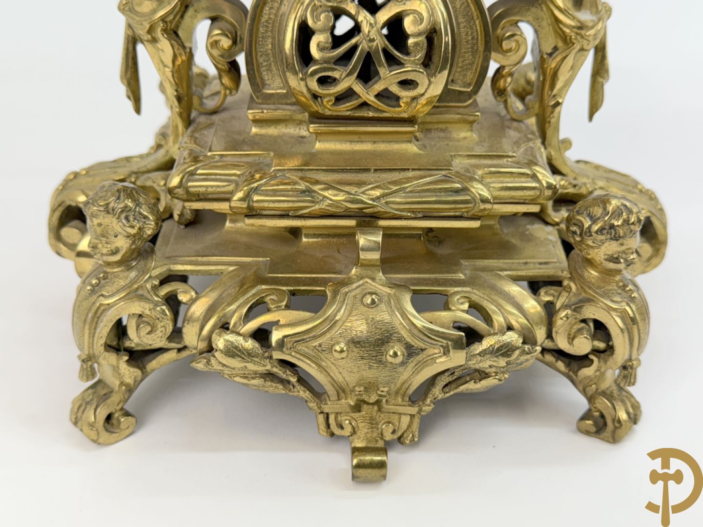 Driedelige bronzen vergulde garntiuur bestaande uit klok met medusahoofden en sfinxen, geflankeerd door paar zevenarmige kandelaars met accanthusranken en sfinxen