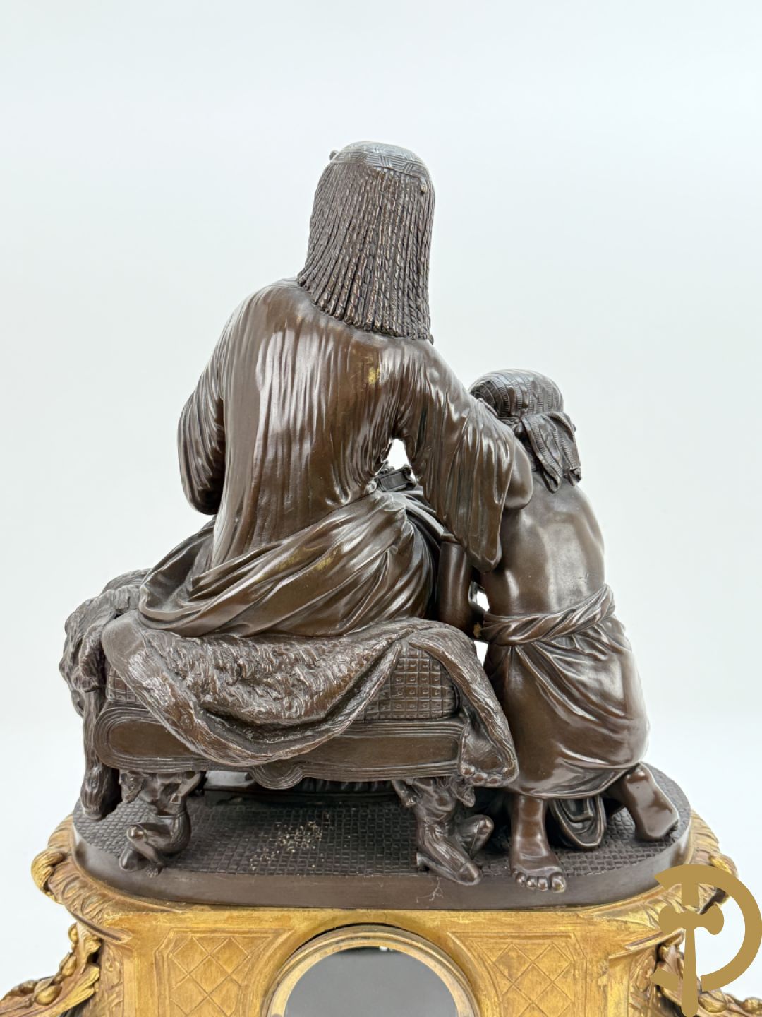 Driedelige bronzen garnituur bestaande uit middenstuk met bronzen vuurvergulde klok, Daubrée gemerkt à Nancy, bovenaan bekroond met Cleopatra met drinkbeker - getekend van Cumberworth sculpteur - geflankeerd door paar cupido