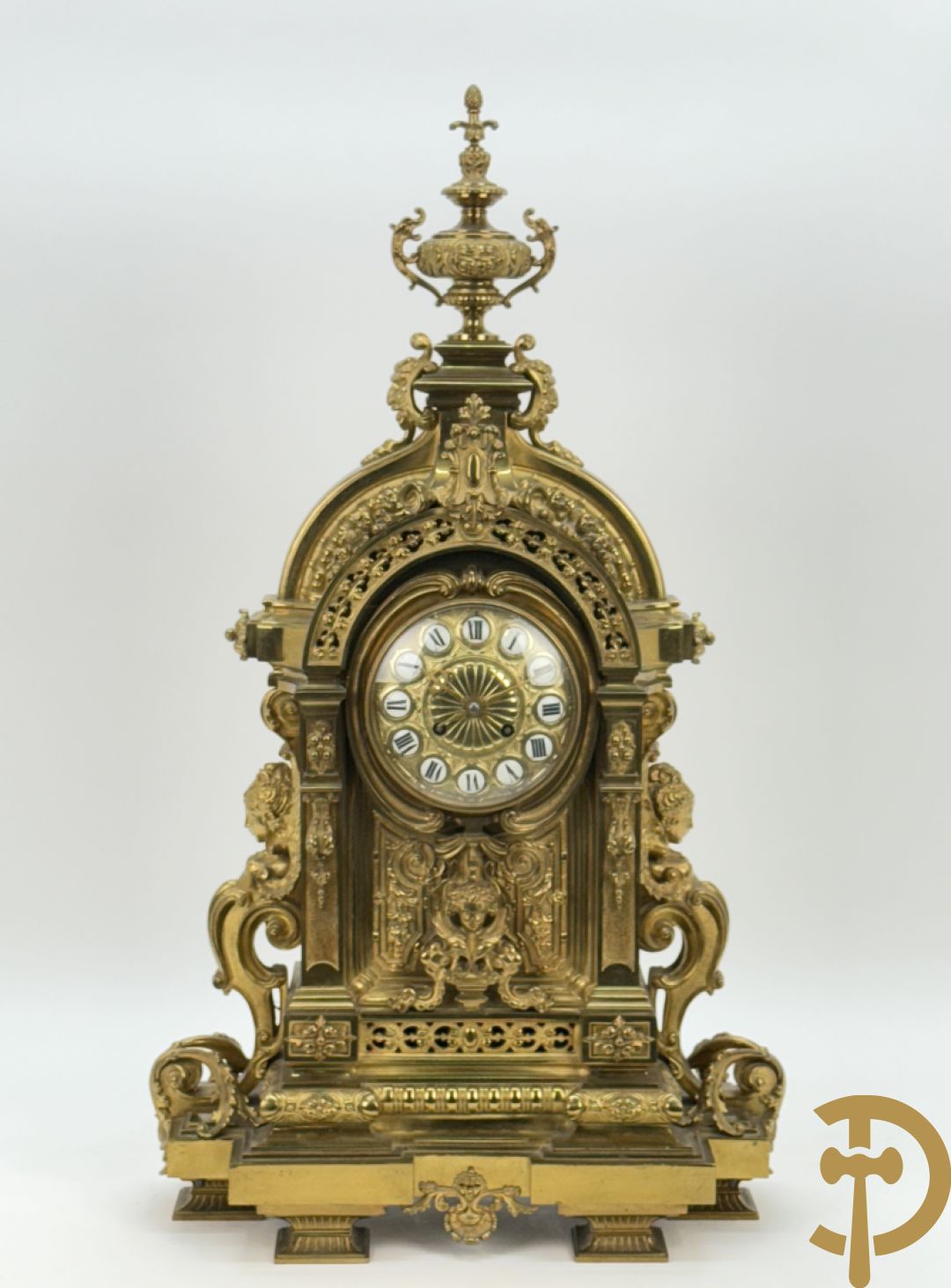 Vuurvergulde bronzen pendule, zijdelings bezet met gevleugelde dames, bovenaan met amfoor
