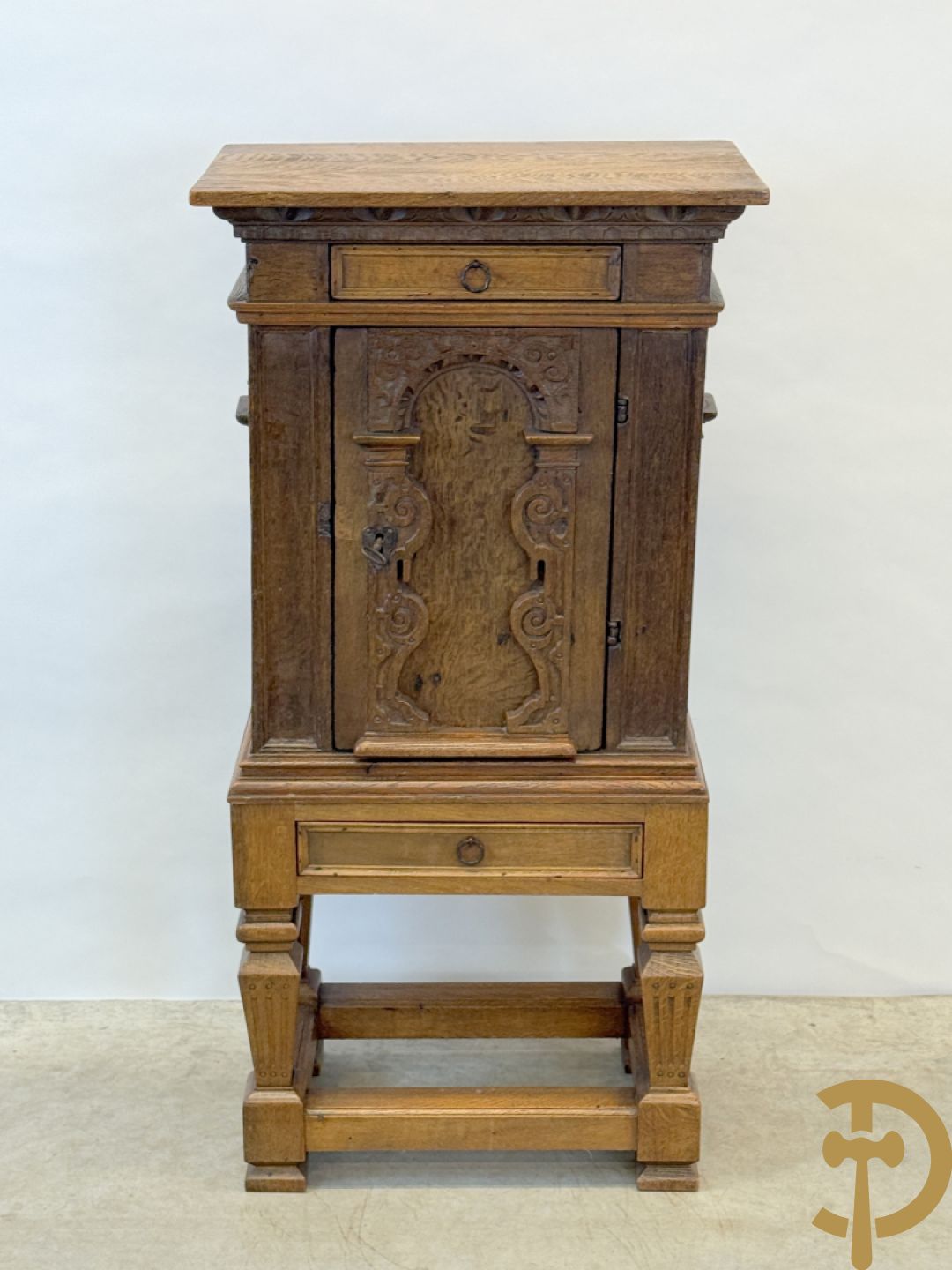 Massief eiken ééndeurskast op onderstel met lade bovenaan, lade onderaan, sculptuur in zijkant en deur