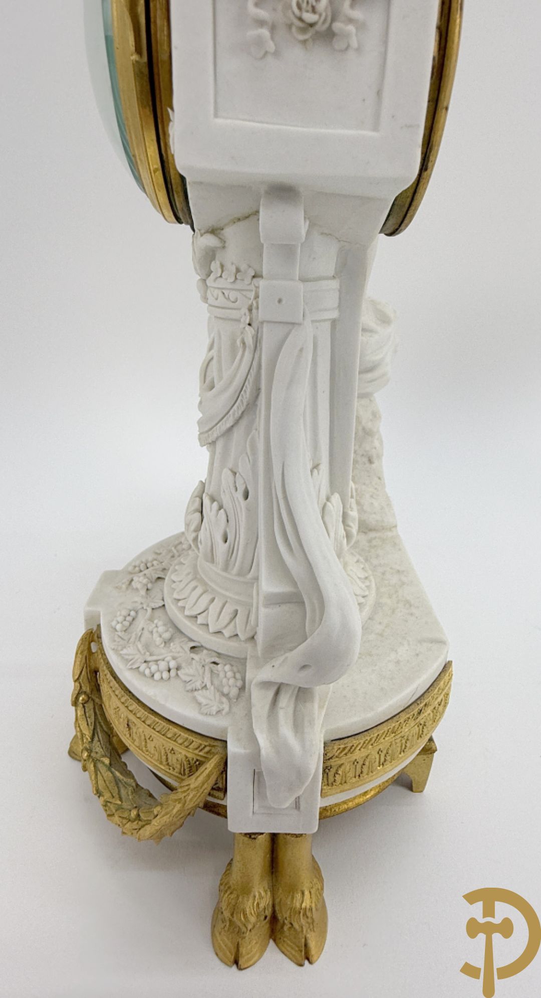 Driedelige porseleinen garnituur met bronsbeslag bestaande uit pendule met dame en amfoor geflankeerd door paar kandelaars bezet met personages