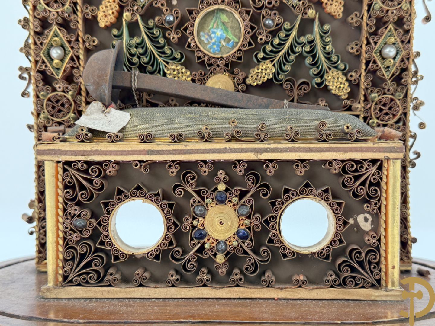 Relikwiehouder in de vorm van een altaar met Christusnagel en omgeven door papperollen - onder stolp