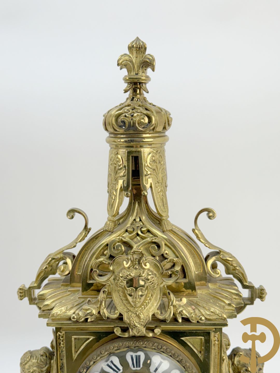 Driedelige bronzen vergulde garntiuur bestaande uit klok met medusahoofden en sfinxen, geflankeerd door paar zevenarmige kandelaars met accanthusranken en sfinxen