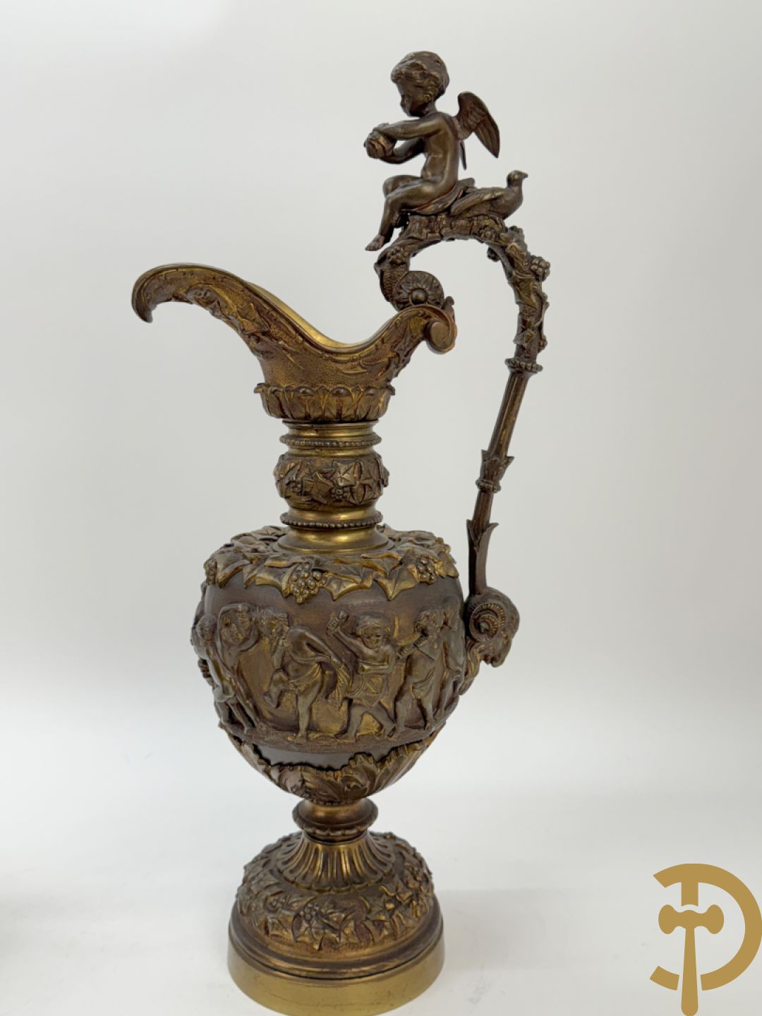 Paar bronzen schenkkannen met basrelief van putti en accanthusranken