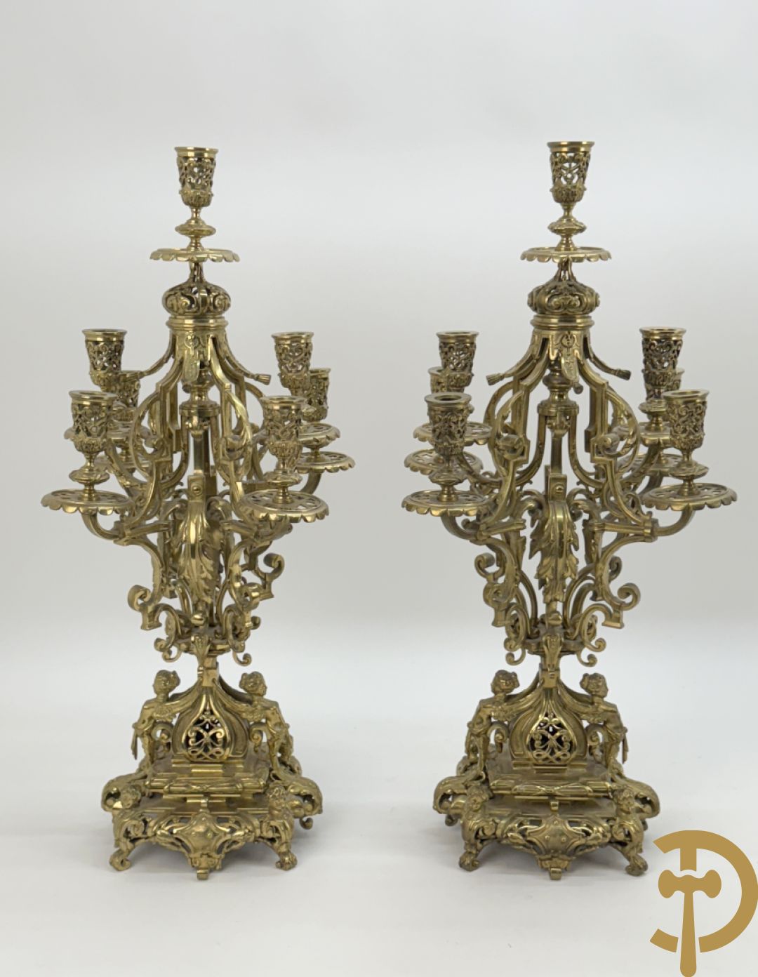 Driedelige bronzen vergulde garntiuur bestaande uit klok met medusahoofden en sfinxen, geflankeerd door paar zevenarmige kandelaars met accanthusranken en sfinxen