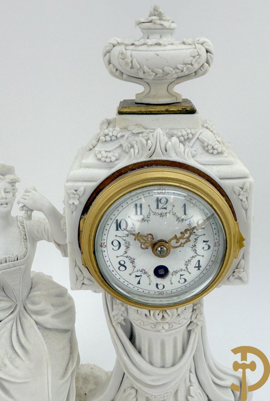 Driedelige porseleinen garnituur met bronsbeslag bestaande uit pendule met dame en amfoor geflankeerd door paar kandelaars bezet met personages