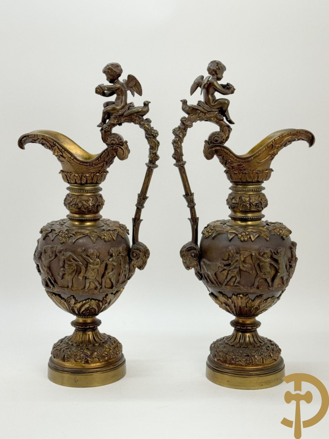 Paar bronzen schenkkannen met basrelief van putti en accanthusranken
