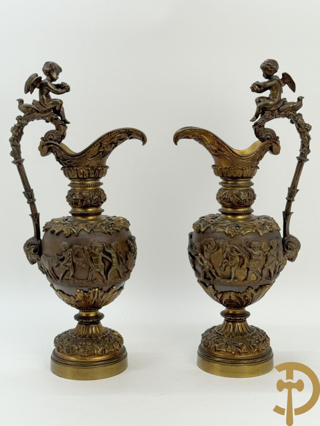 Paar bronzen schenkkannen met basrelief van putti en accanthusranken