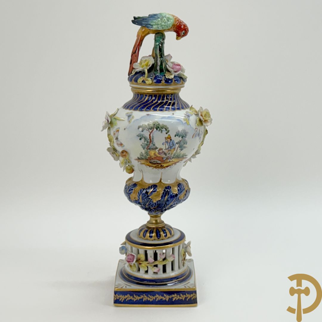 Porseleinen siervaas met handbeschilderd geanimeerd decor bezet met basrelief van bloemen en bovenaan bekroond met deksel met vogel
