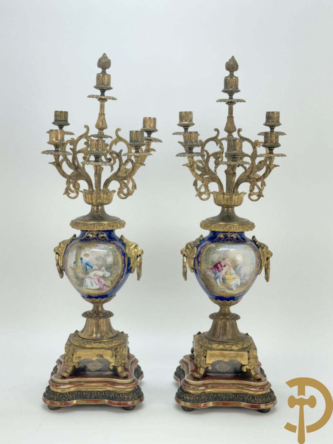Driedelige vergulde bronzen garnituur bestaande uit pendule met blauw porseleinen coupe geflankeerd door 2 cupido