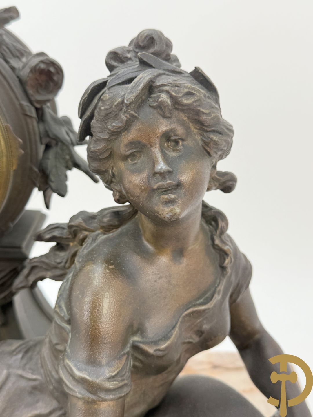 Driedelige kunstbronzen garnituur bestaande uit klok met liggende dame met amfoor op marmeren basis, geflankeerd door paar cassolettes met cupido