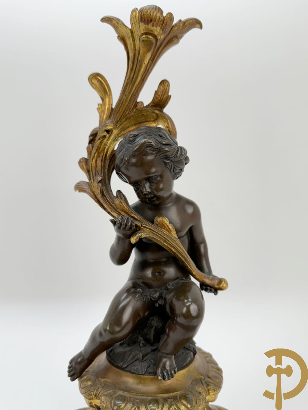 Driedelige bronzen garnituur bestaande uit middenstuk met bronzen vuurvergulde klok, Daubrée gemerkt à Nancy, bovenaan bekroond met Cleopatra met drinkbeker - getekend van Cumberworth sculpteur - geflankeerd door paar cupido