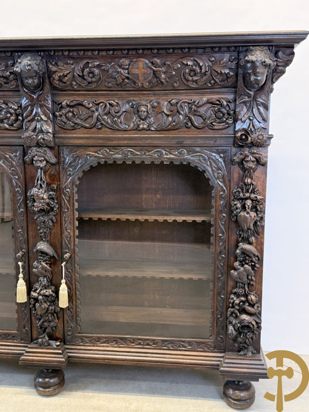 Tweedeursvitrine met Neo Renaissance sculptuur, bovenaan mlet cupidohoofden, bloemen en accanthusranken