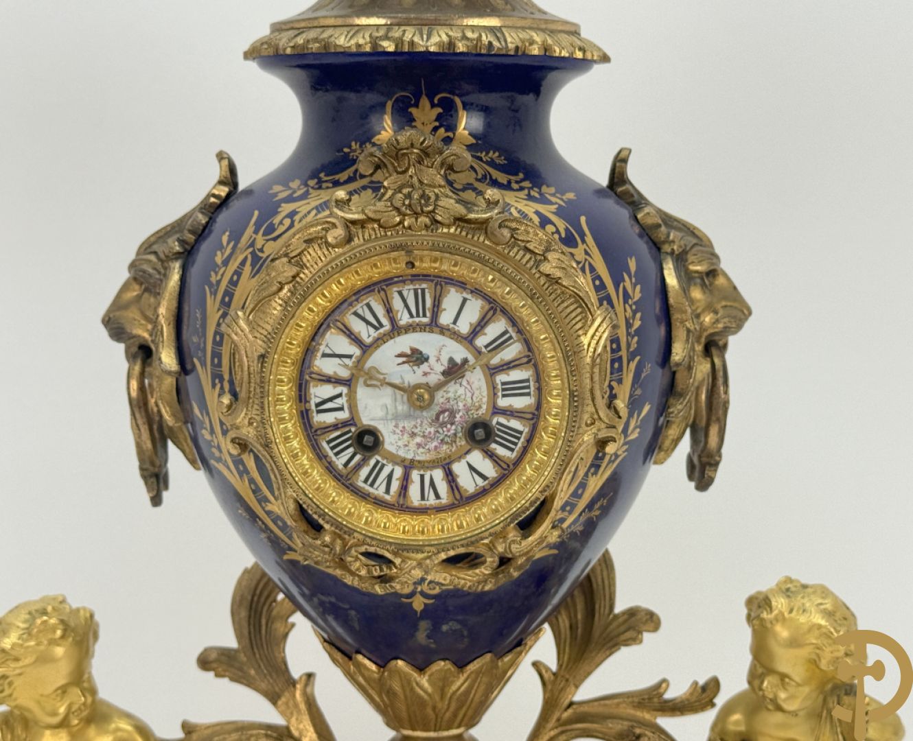 Driedelige vergulde bronzen garnituur bestaande uit pendule met blauw porseleinen coupe geflankeerd door 2 cupido