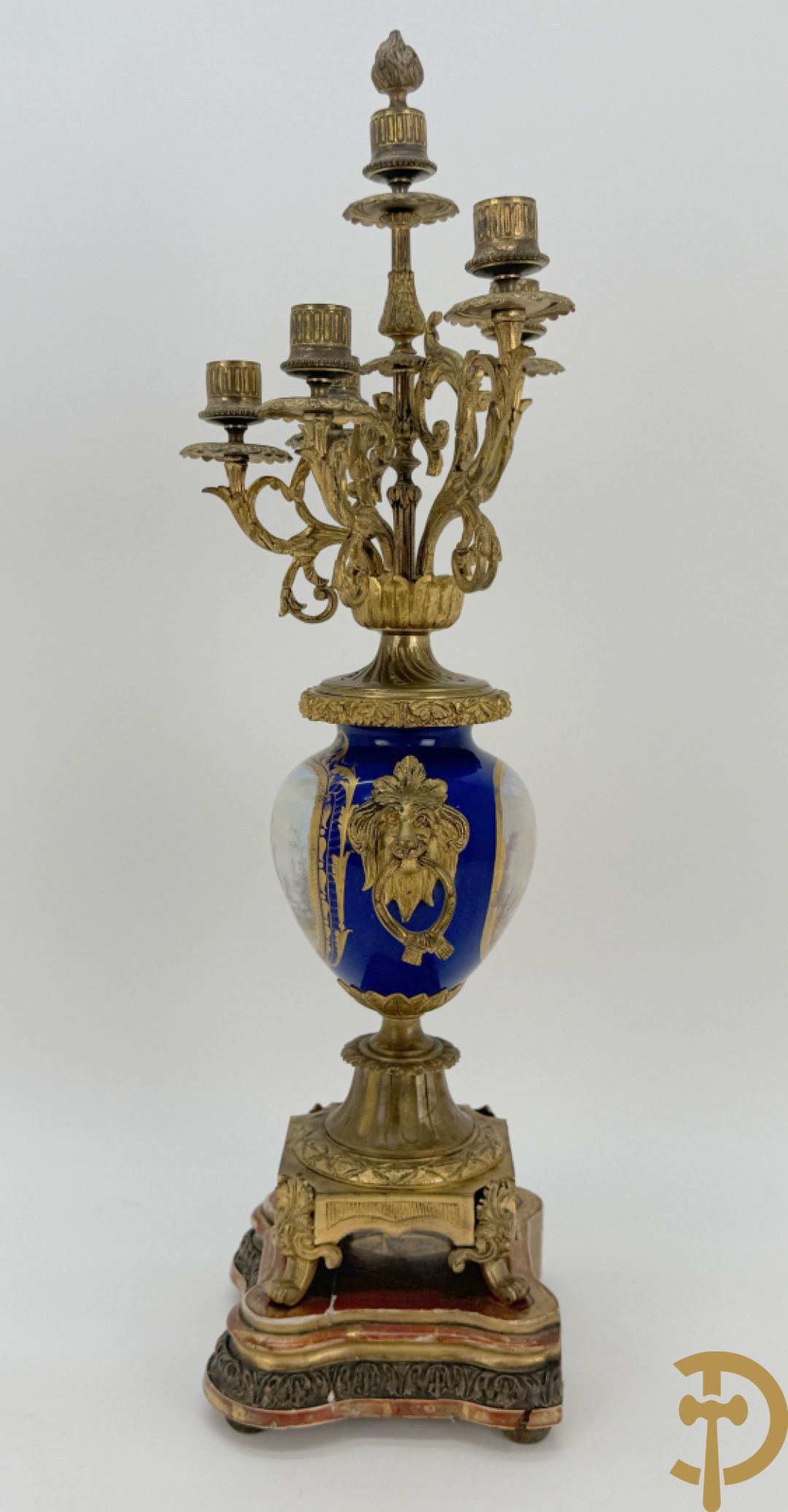 Driedelige vergulde bronzen garnituur bestaande uit pendule met blauw porseleinen coupe geflankeerd door 2 cupido