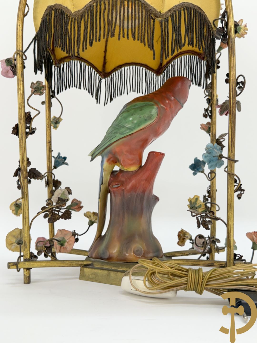 Handgekleurde porseleinen papegaai onder koperen boog met bloemen bezet, als lampadaire