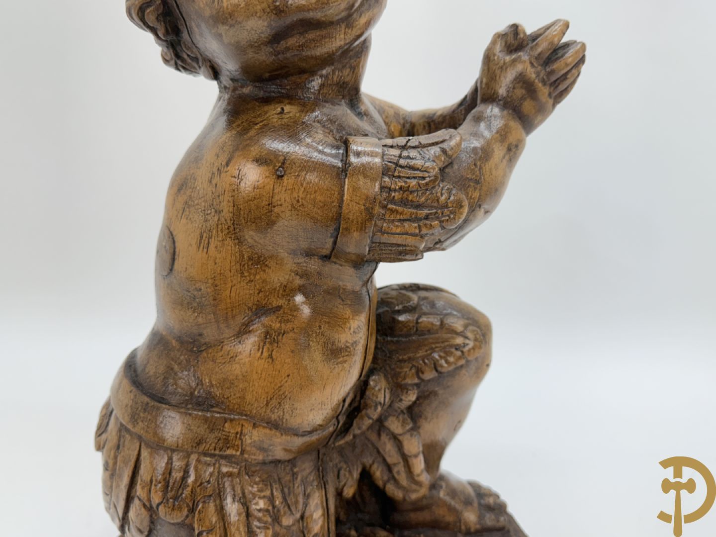Houtgesculpteerde cupido met gevouwen handen en pluimen