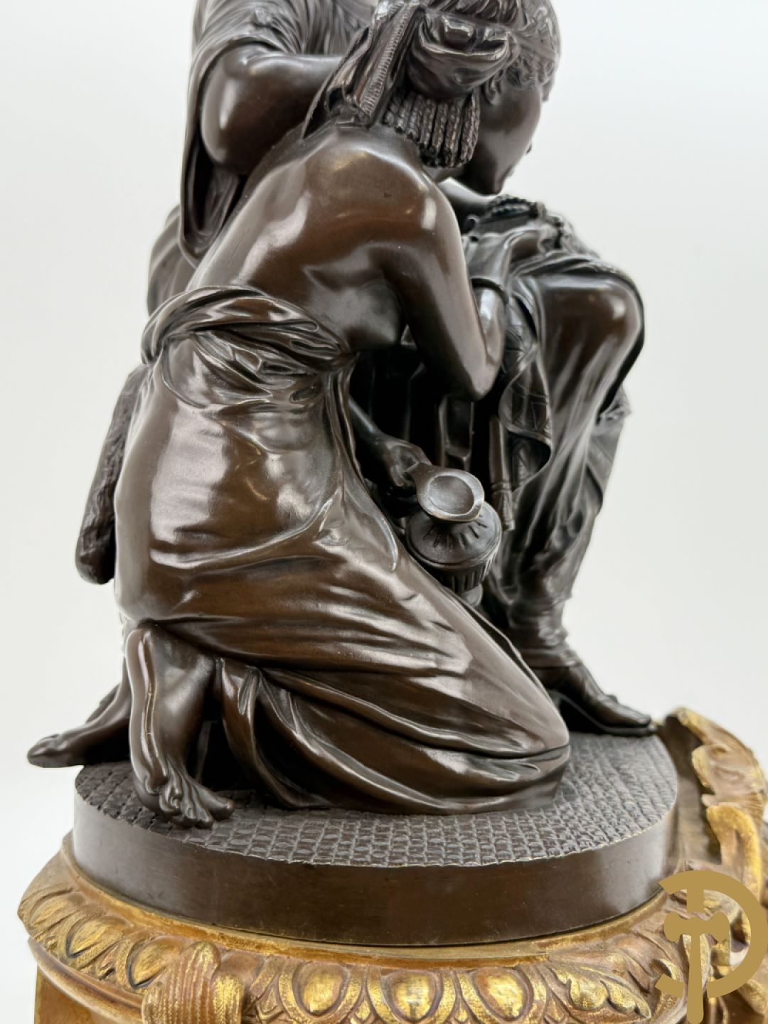 Driedelige bronzen garnituur bestaande uit middenstuk met bronzen vuurvergulde klok, Daubrée gemerkt à Nancy, bovenaan bekroond met Cleopatra met drinkbeker - getekend van Cumberworth sculpteur - geflankeerd door paar cupido