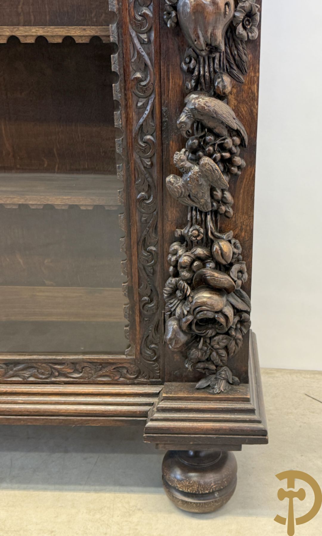 Tweedeursvitrine met Neo Renaissance sculptuur, bovenaan mlet cupidohoofden, bloemen en accanthusranken