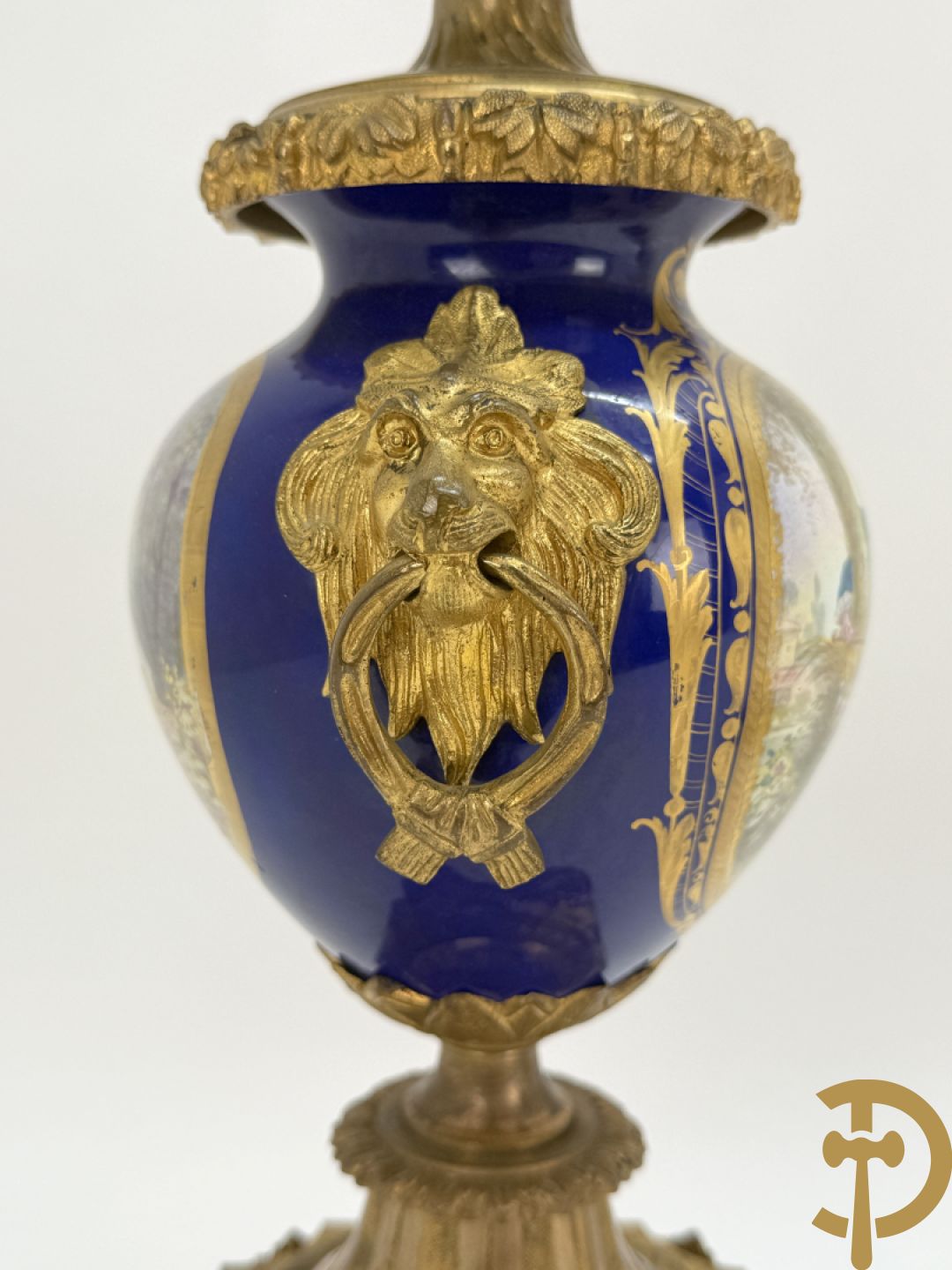 Driedelige vergulde bronzen garnituur bestaande uit pendule met blauw porseleinen coupe geflankeerd door 2 cupido