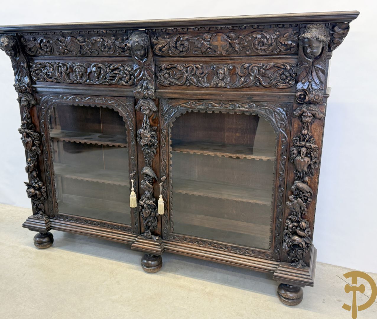 Tweedeursvitrine met Neo Renaissance sculptuur, bovenaan mlet cupidohoofden, bloemen en accanthusranken