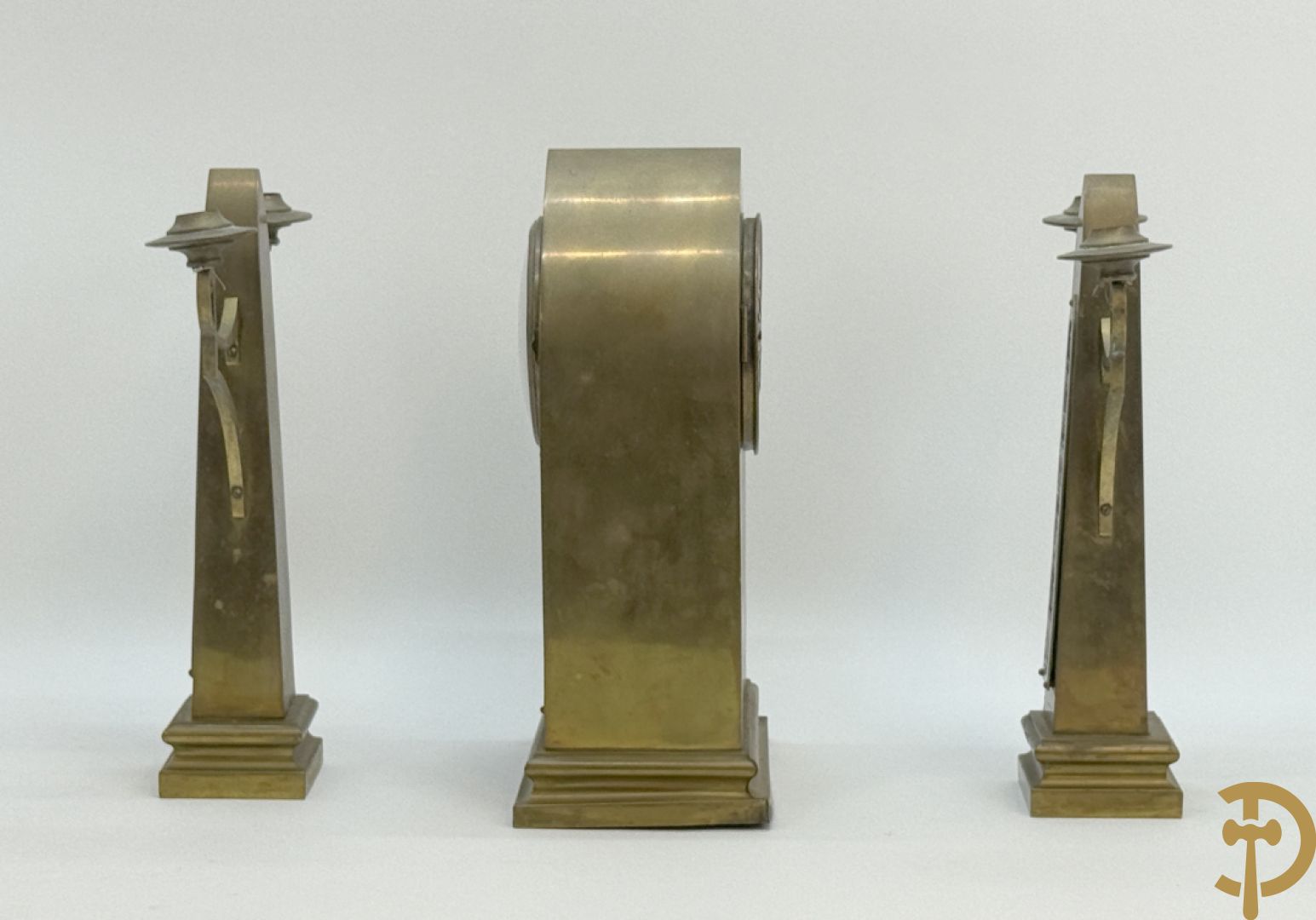 Driedelige koperen Art Nouveau garnituur bestaande uit kapelvormige pendule geflankeerd door paar kandelaars