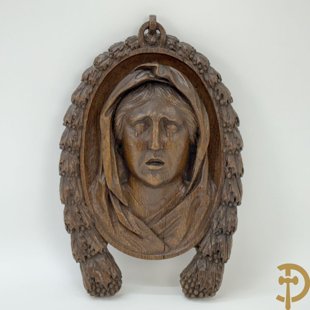 Houtgesculpteerd basrelief van wenende dame in cartouche met accanthusranken