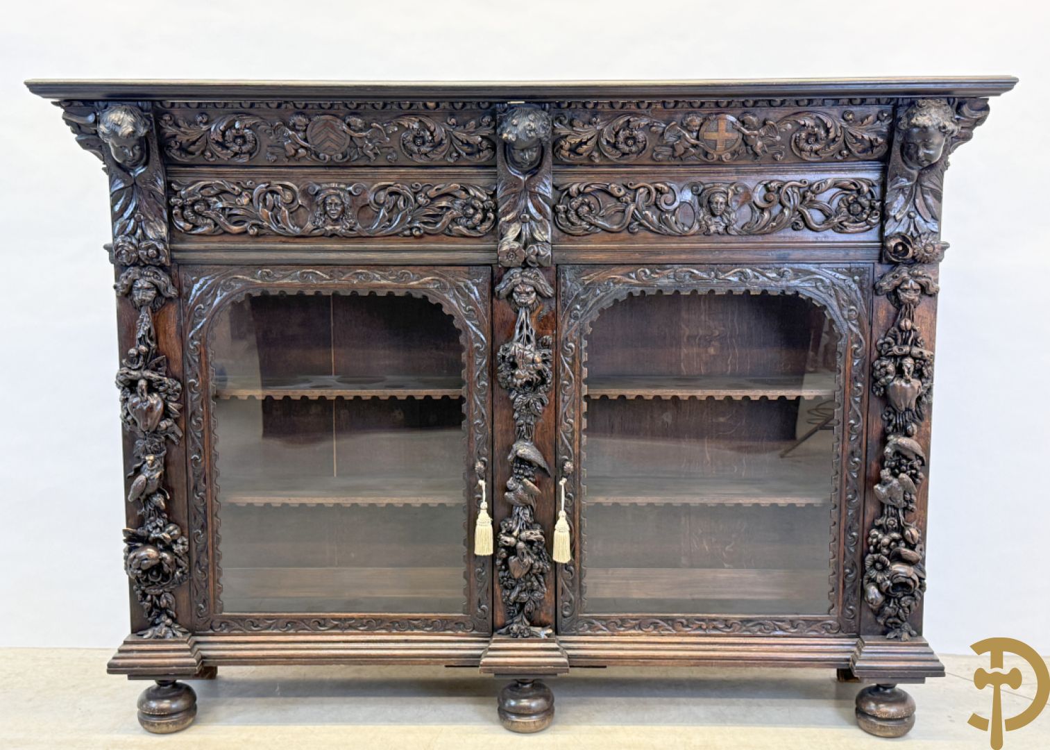 Tweedeursvitrine met Neo Renaissance sculptuur, bovenaan mlet cupidohoofden, bloemen en accanthusranken
