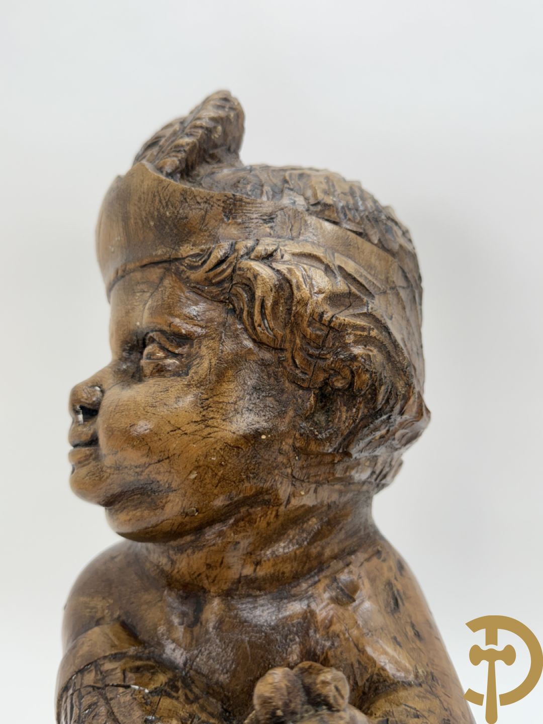 Houtgesculpteerde cupido met gevouwen handen en pluimen