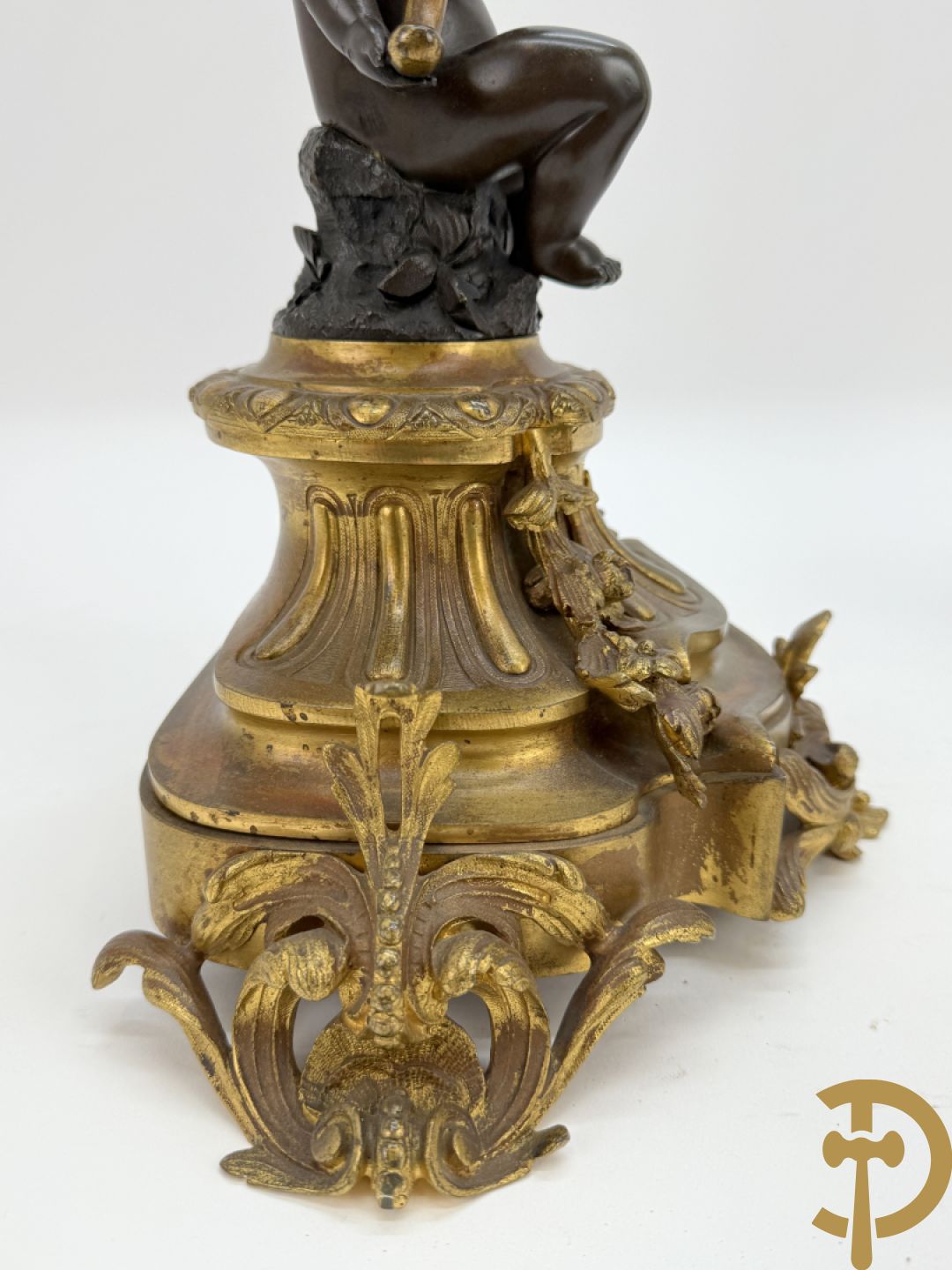 Driedelige bronzen garnituur bestaande uit middenstuk met bronzen vuurvergulde klok, Daubrée gemerkt à Nancy, bovenaan bekroond met Cleopatra met drinkbeker - getekend van Cumberworth sculpteur - geflankeerd door paar cupido