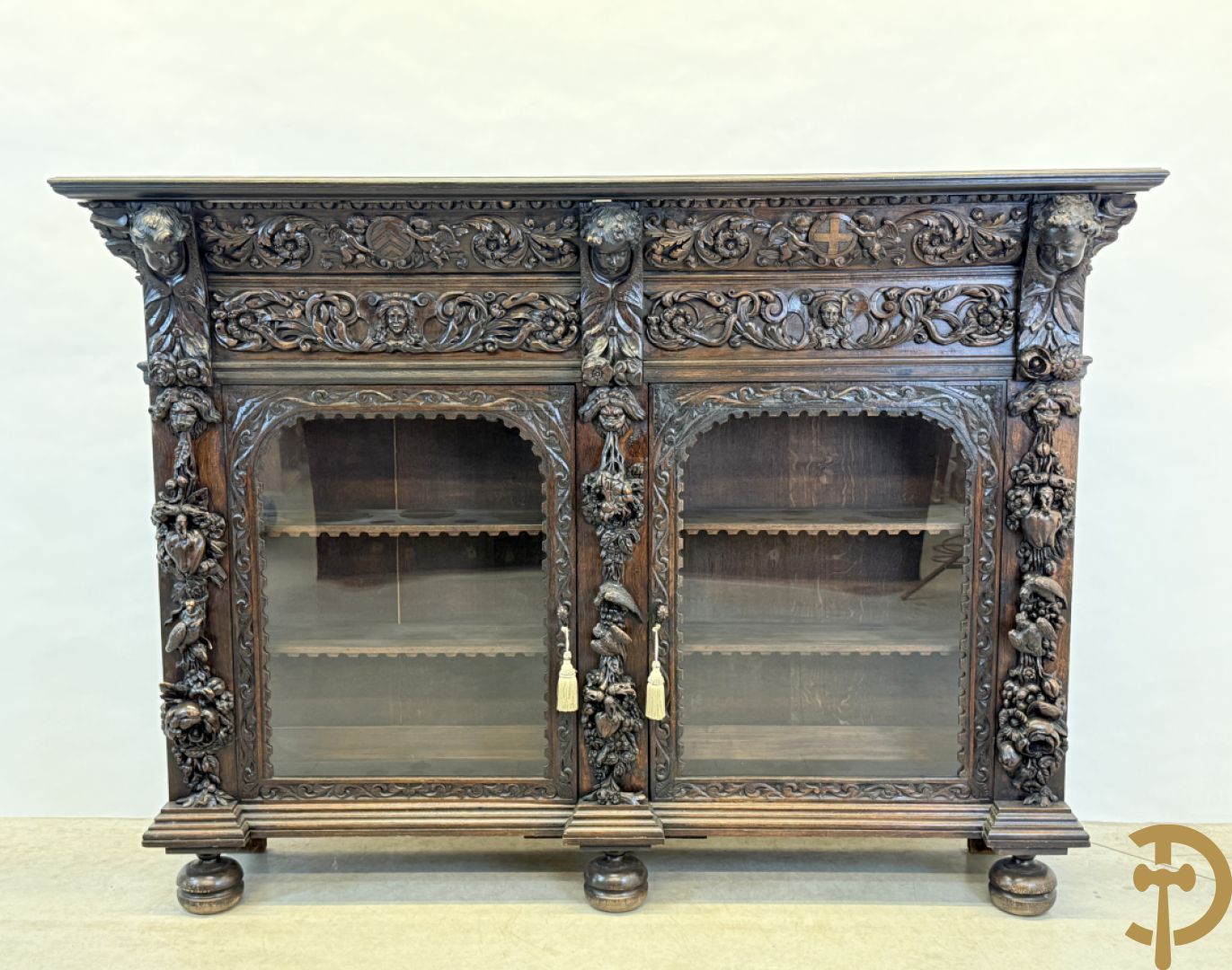 Tweedeursvitrine met Neo Renaissance sculptuur, bovenaan mlet cupidohoofden, bloemen en accanthusranken