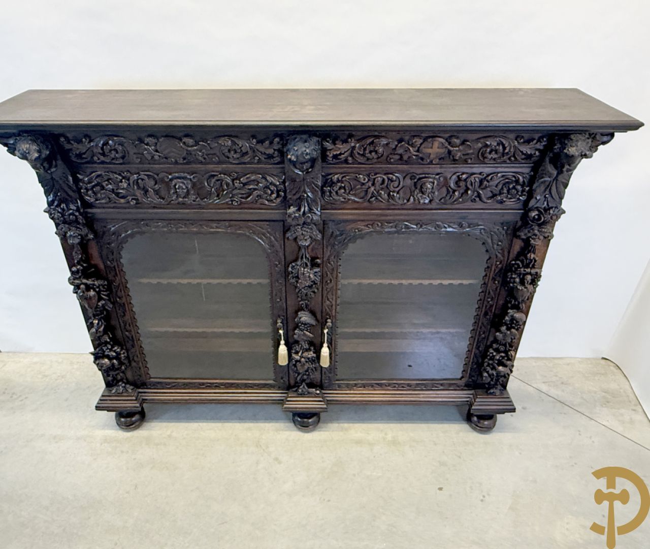 Tweedeursvitrine met Neo Renaissance sculptuur, bovenaan mlet cupidohoofden, bloemen en accanthusranken