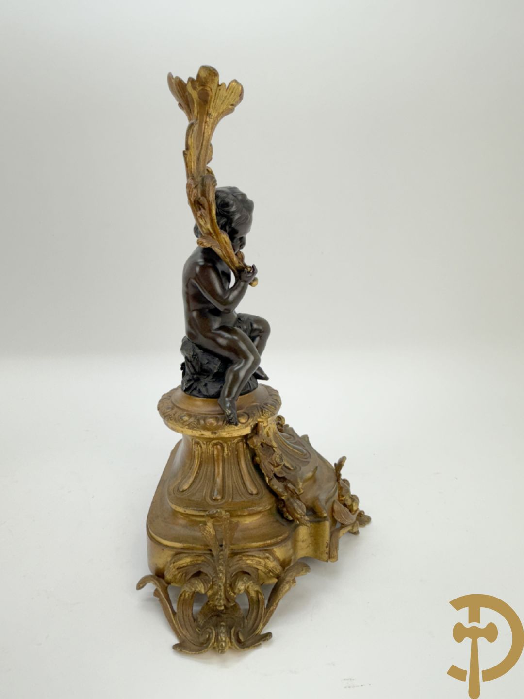 Driedelige bronzen garnituur bestaande uit middenstuk met bronzen vuurvergulde klok, Daubrée gemerkt à Nancy, bovenaan bekroond met Cleopatra met drinkbeker - getekend van Cumberworth sculpteur - geflankeerd door paar cupido