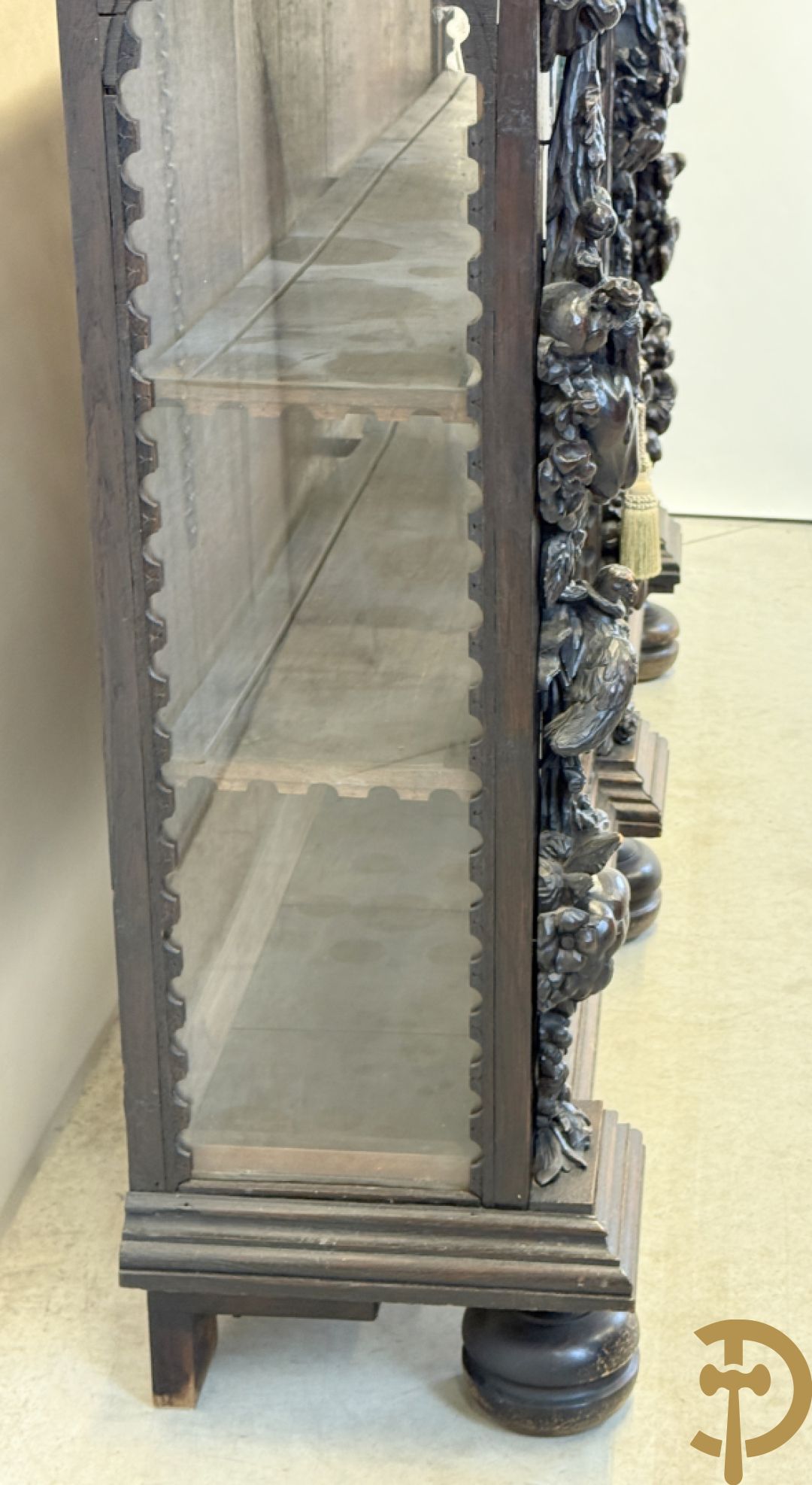 Tweedeursvitrine met Neo Renaissance sculptuur, bovenaan mlet cupidohoofden, bloemen en accanthusranken