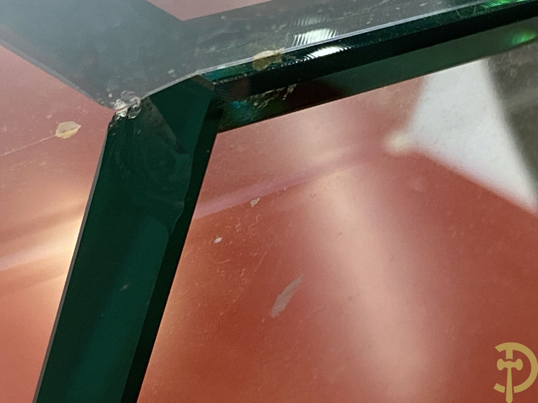 Design salontafel met glazen gepolijst blad op rood gelakte driehoekig prisma sokkel