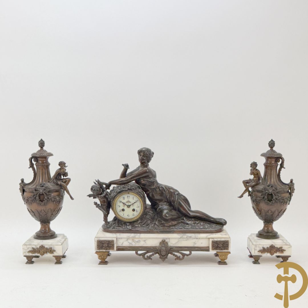 Driedelige schouwgarnituur met centrale pendule met liggende dame en cupido, geflankeerd door paar cassolettes met elegante dame
