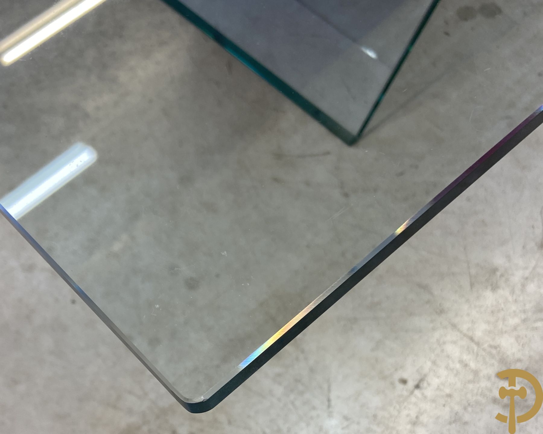 Design salontafel met glazen gepolijst blad op rood gelakte driehoekig prisma sokkel