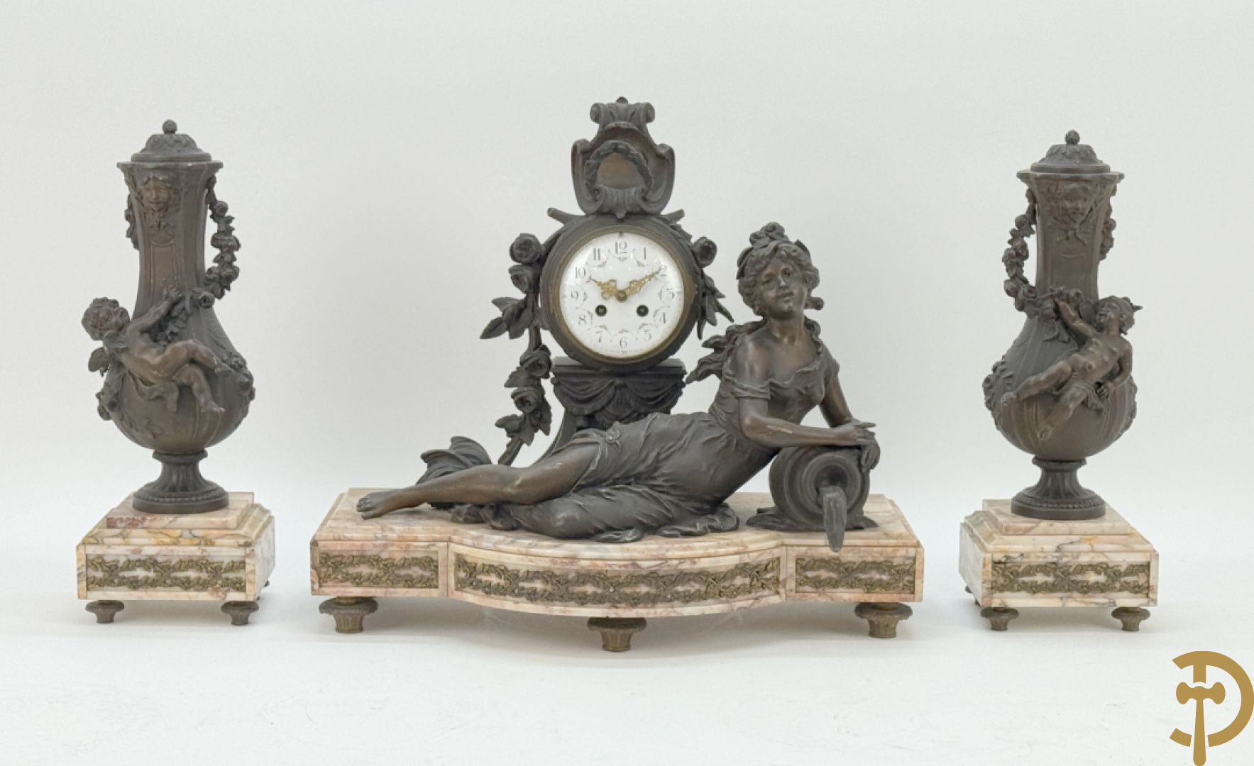 Driedelige kunstbronzen garnituur bestaande uit klok met liggende dame met amfoor op marmeren basis, geflankeerd door paar cassolettes met cupido