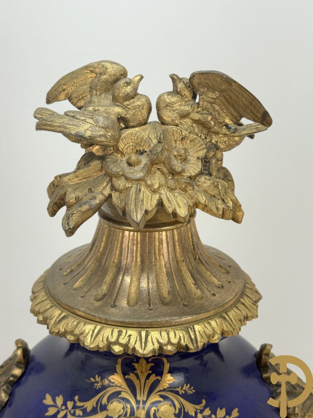 Driedelige vergulde bronzen garnituur bestaande uit pendule met blauw porseleinen coupe geflankeerd door 2 cupido