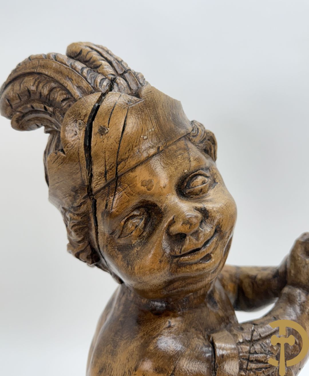 Houtgesculpteerde cupido met gevouwen handen en pluimen