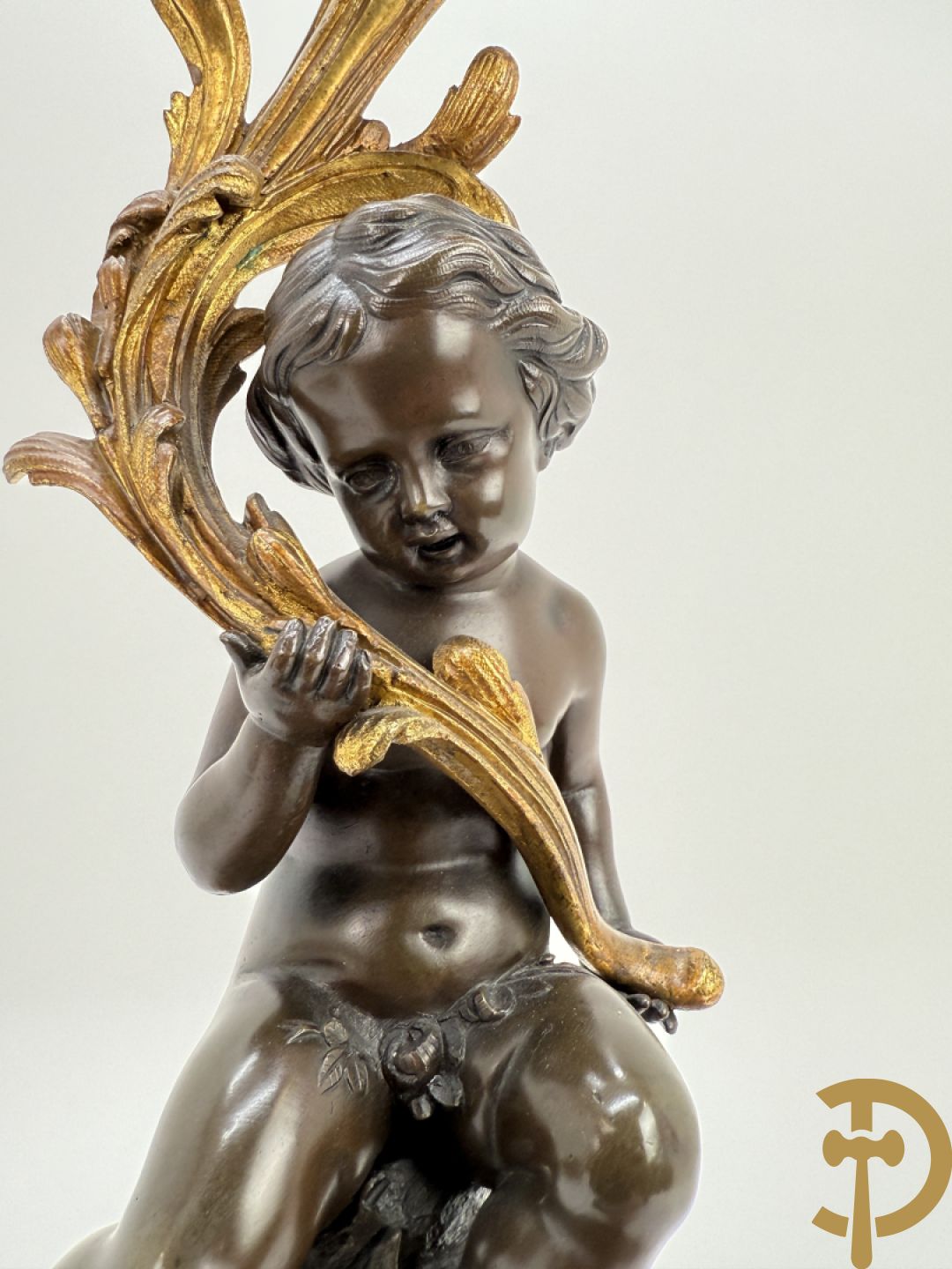 Driedelige bronzen garnituur bestaande uit middenstuk met bronzen vuurvergulde klok, Daubrée gemerkt à Nancy, bovenaan bekroond met Cleopatra met drinkbeker - getekend van Cumberworth sculpteur - geflankeerd door paar cupido