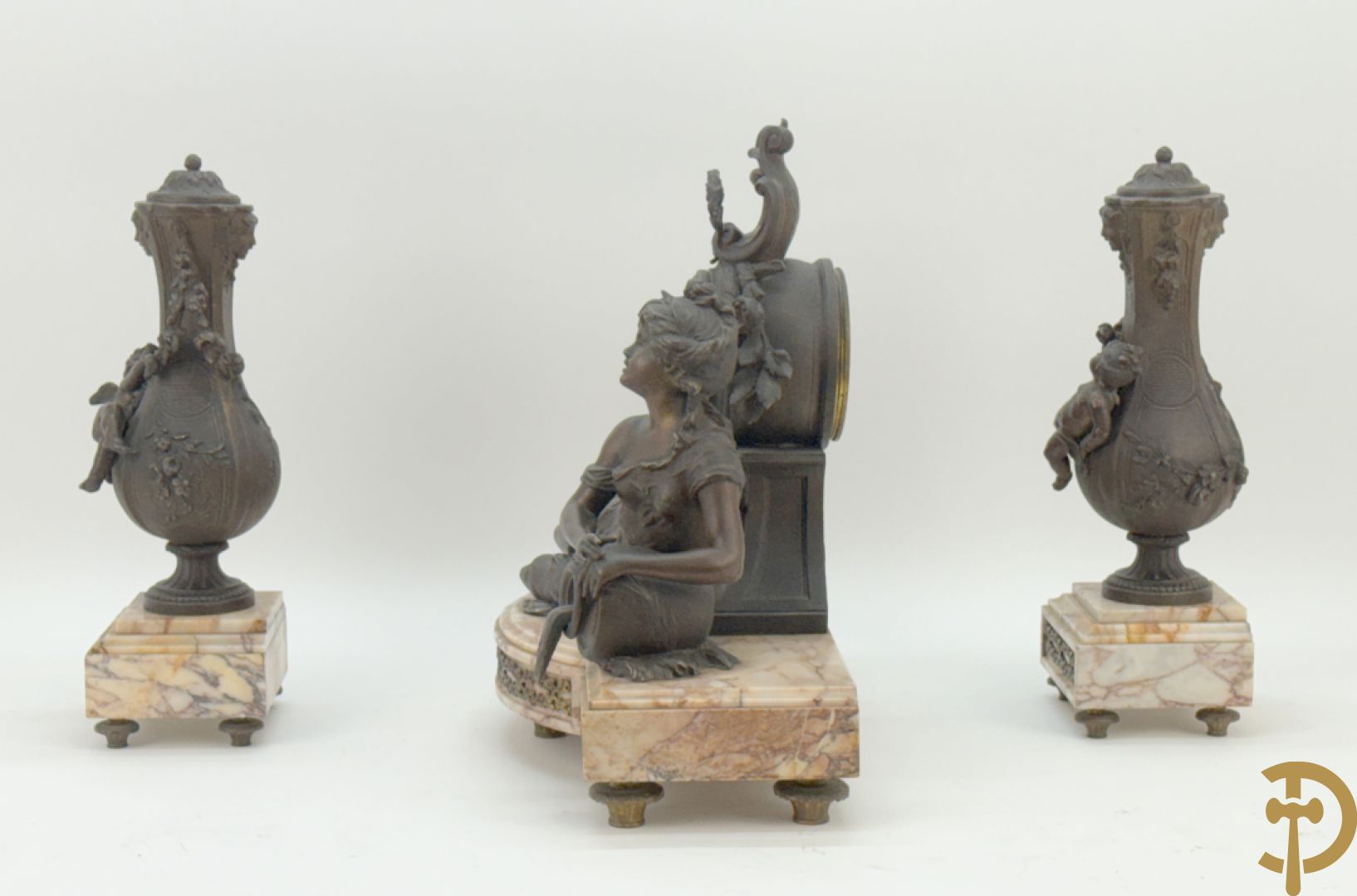 Driedelige kunstbronzen garnituur bestaande uit klok met liggende dame met amfoor op marmeren basis, geflankeerd door paar cassolettes met cupido