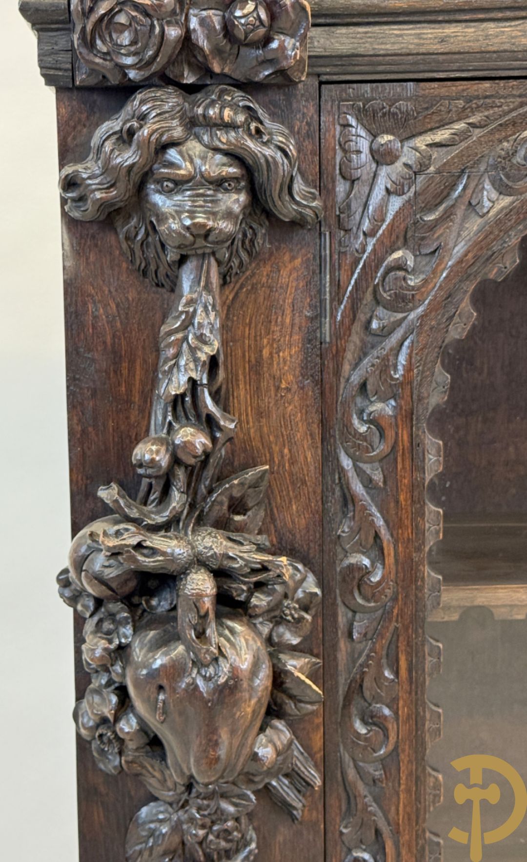 Tweedeursvitrine met Neo Renaissance sculptuur, bovenaan mlet cupidohoofden, bloemen en accanthusranken