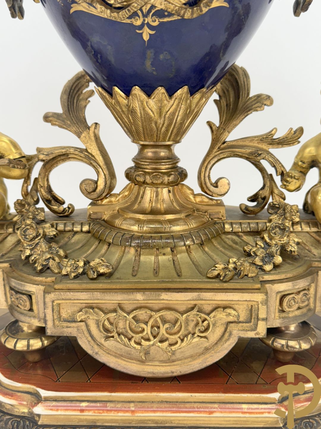 Driedelige vergulde bronzen garnituur bestaande uit pendule met blauw porseleinen coupe geflankeerd door 2 cupido