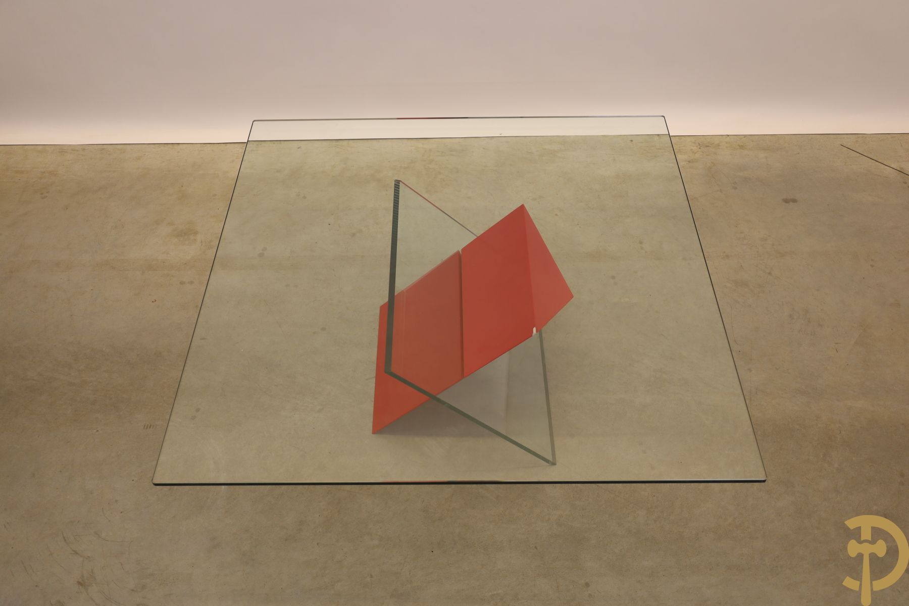 Design salontafel met glazen gepolijst blad op rood gelakte driehoekig prisma sokkel