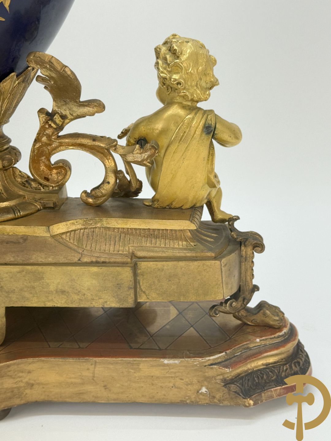 Driedelige vergulde bronzen garnituur bestaande uit pendule met blauw porseleinen coupe geflankeerd door 2 cupido