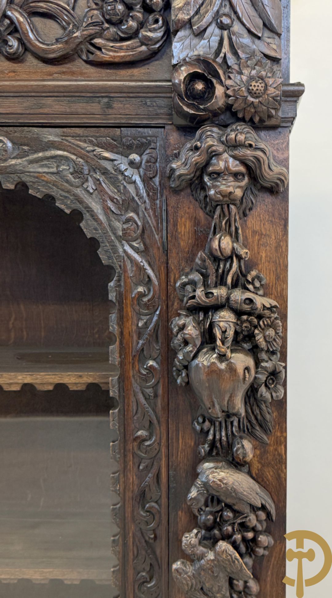 Tweedeursvitrine met Neo Renaissance sculptuur, bovenaan mlet cupidohoofden, bloemen en accanthusranken